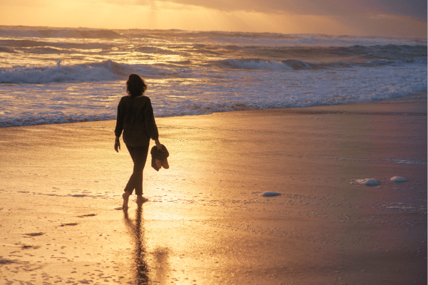midlife burnout in women as she walks along the beach